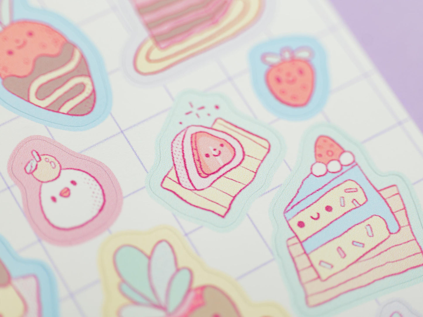 Pastel-colored stickers of desserts and fruits on a grid background