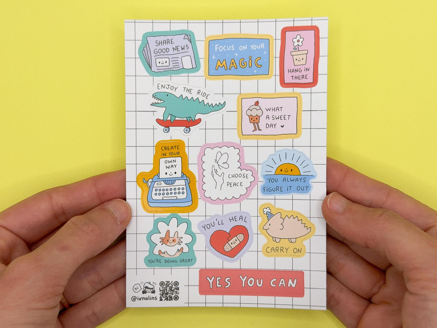 Hand holding a card with colorful motivational stickers on a yellow background