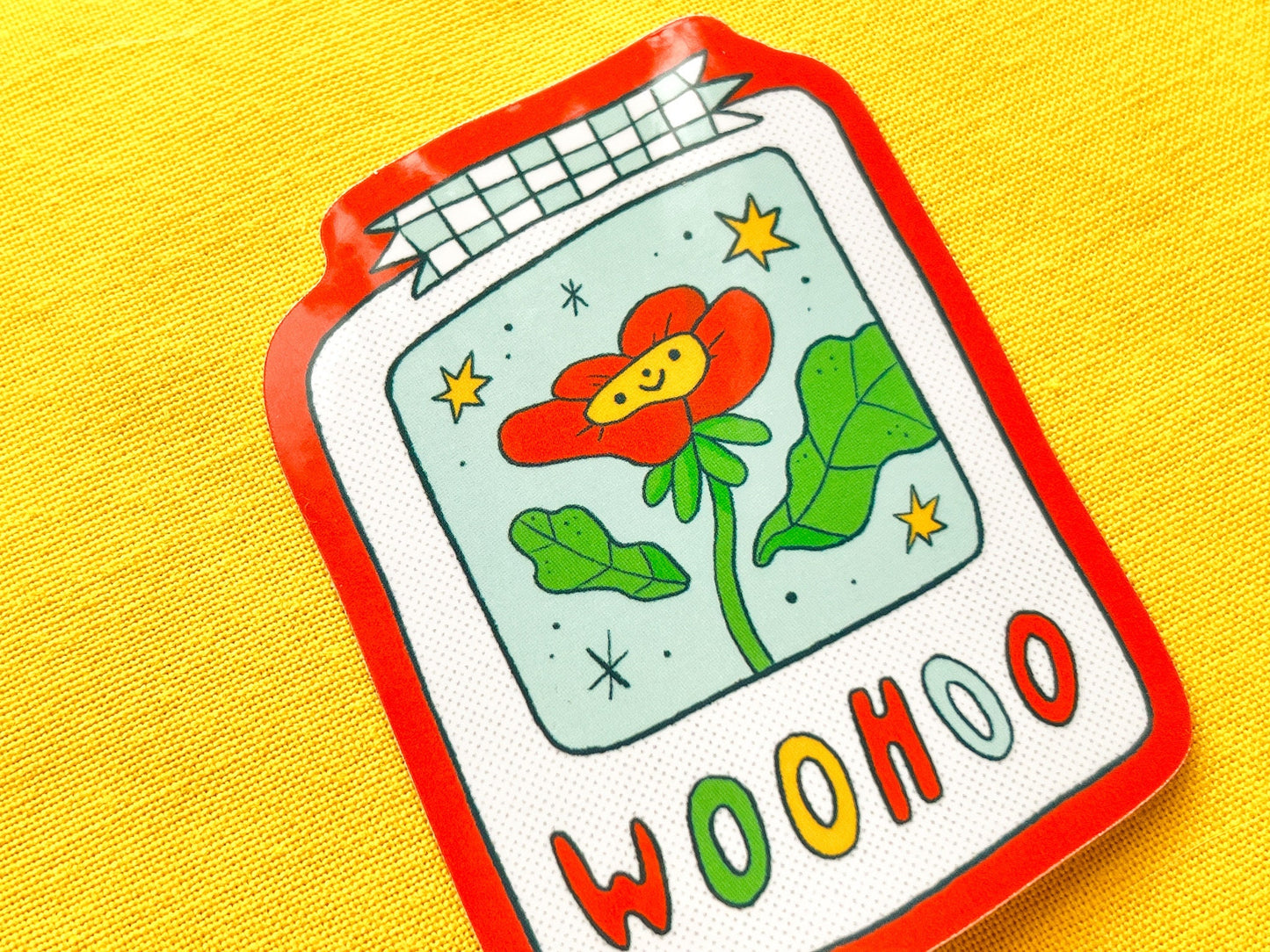 Colorful sticker of a polaroid with a flower and 'WOOHOO' text on a yellow background