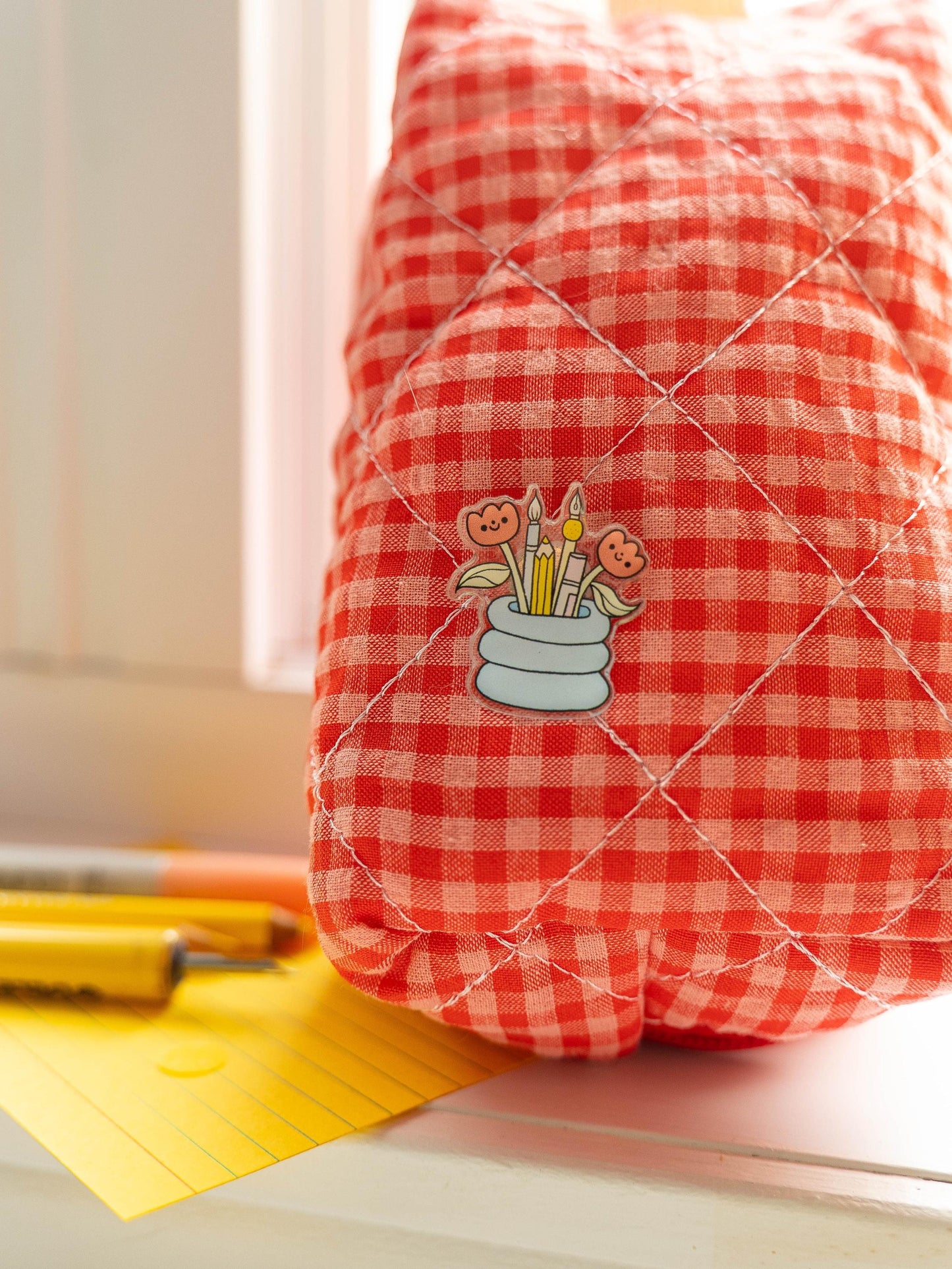 Red and white checkered bag with a pin on a light surface