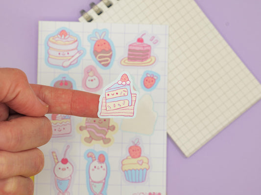 Sheet of cute cartoon stickers with a hand holding one, on a purple background.