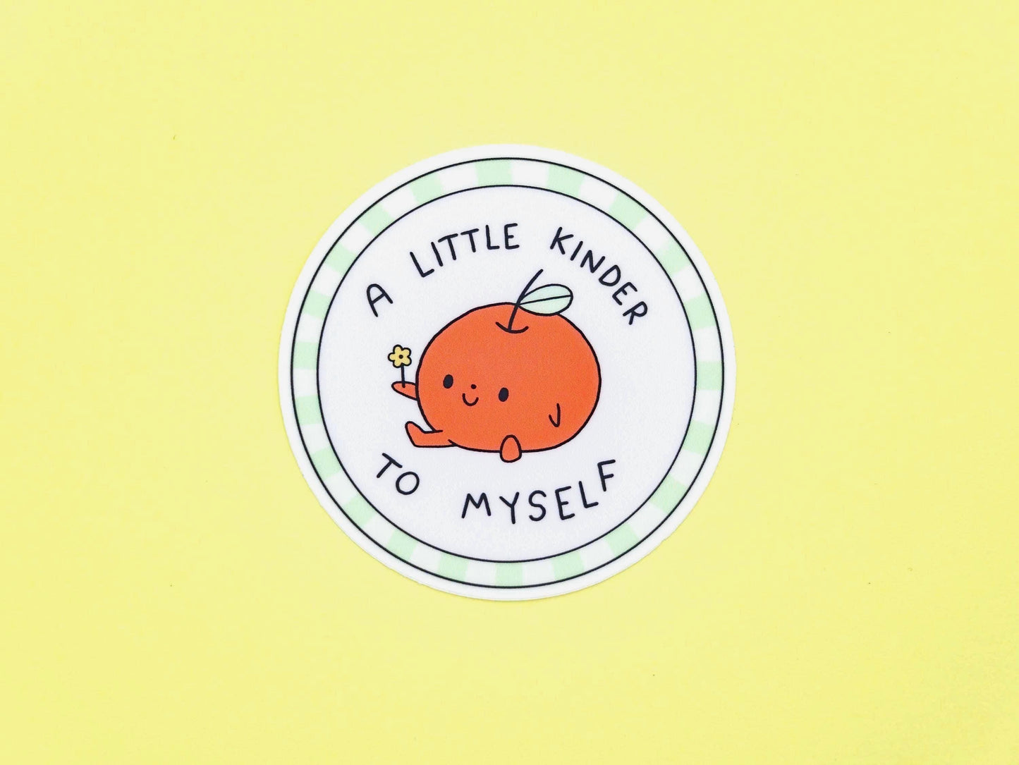 Circular sticker with a cartoon apple and text 'A little kinder to myself' on a yellow background