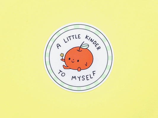 Circular sticker with a cartoon apple and text 'A little kinder to myself' on a yellow background