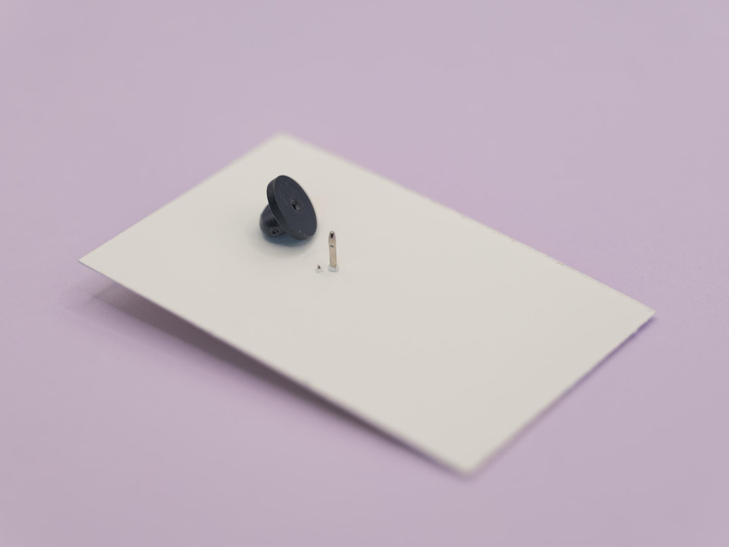 Black rubber clutch on a white rectangular card against a light purple background