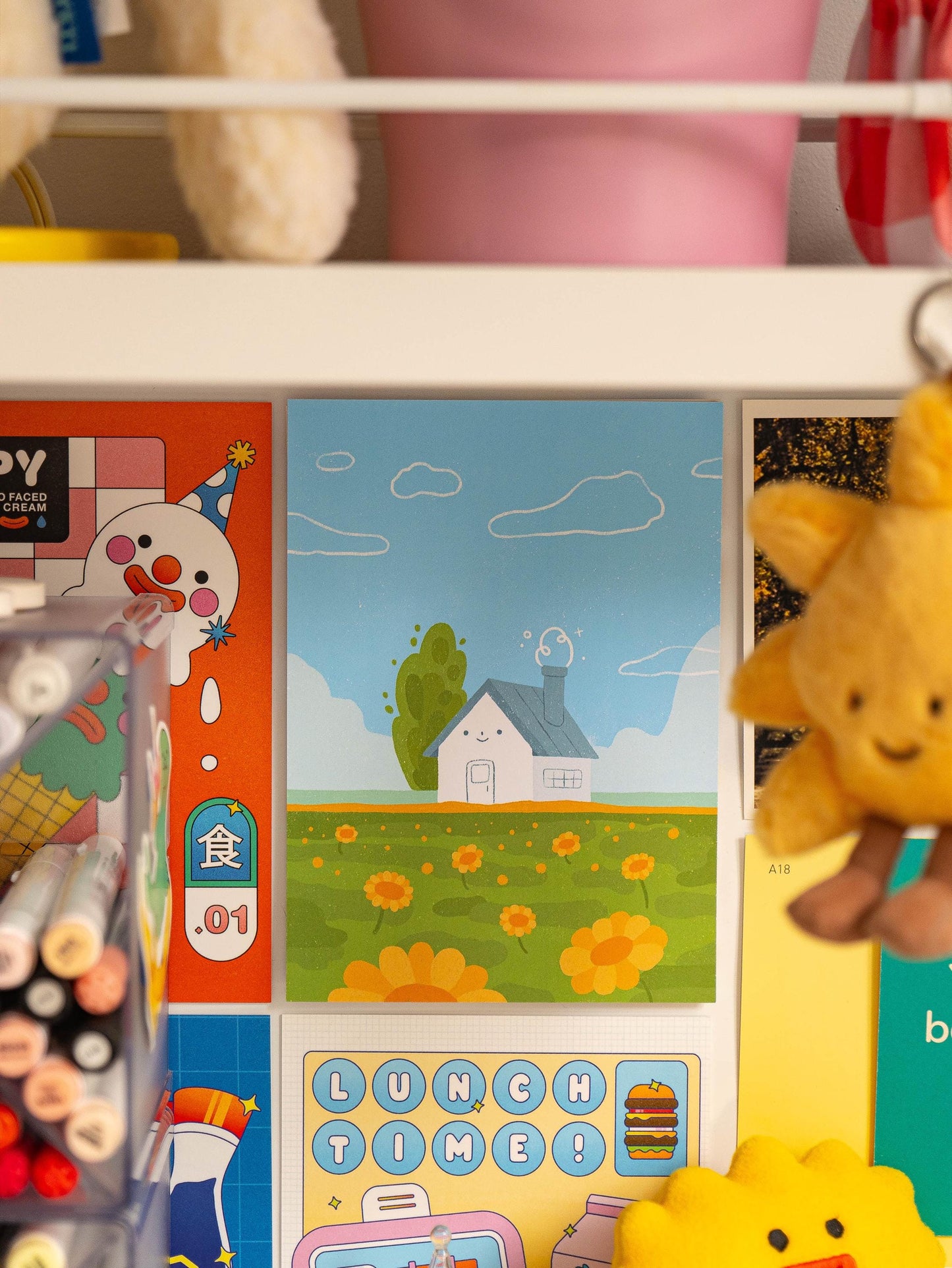Art print on a wall with colorful illustrations on a shelf.
