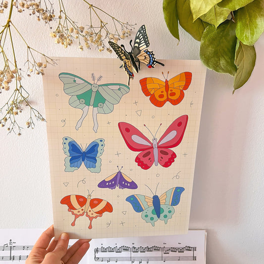 Colorful butterfly illustrations on a poster held by a hand with a plant and music sheet in the background.