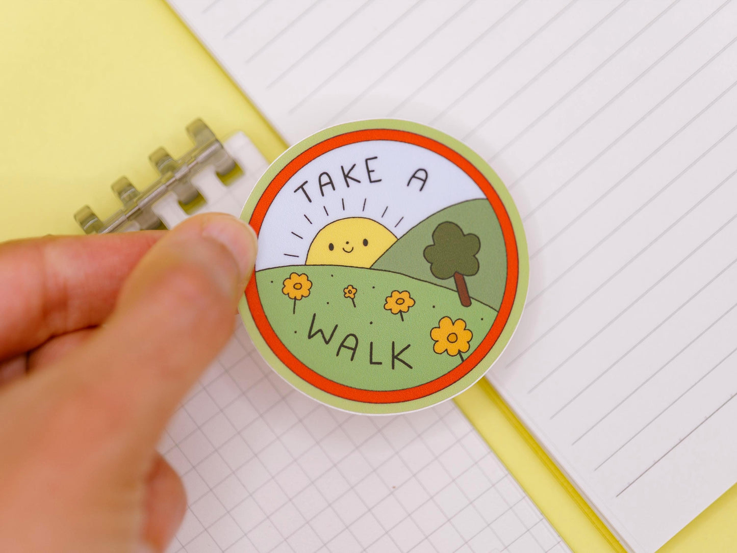 Circular sticker with 'Take a Walk' text held over lined paper
