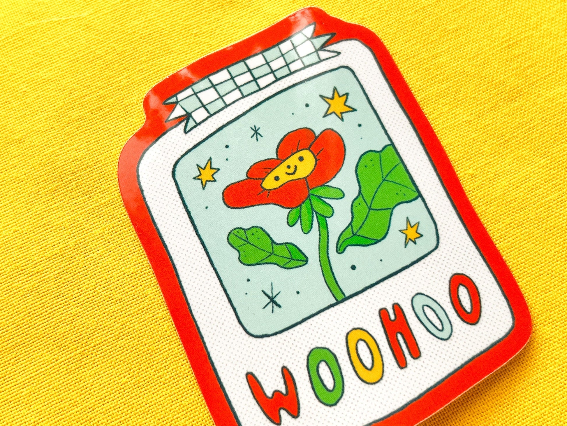 Colorful sticker of a polaroid with a flower and 'WOOHOO' text on a yellow background
