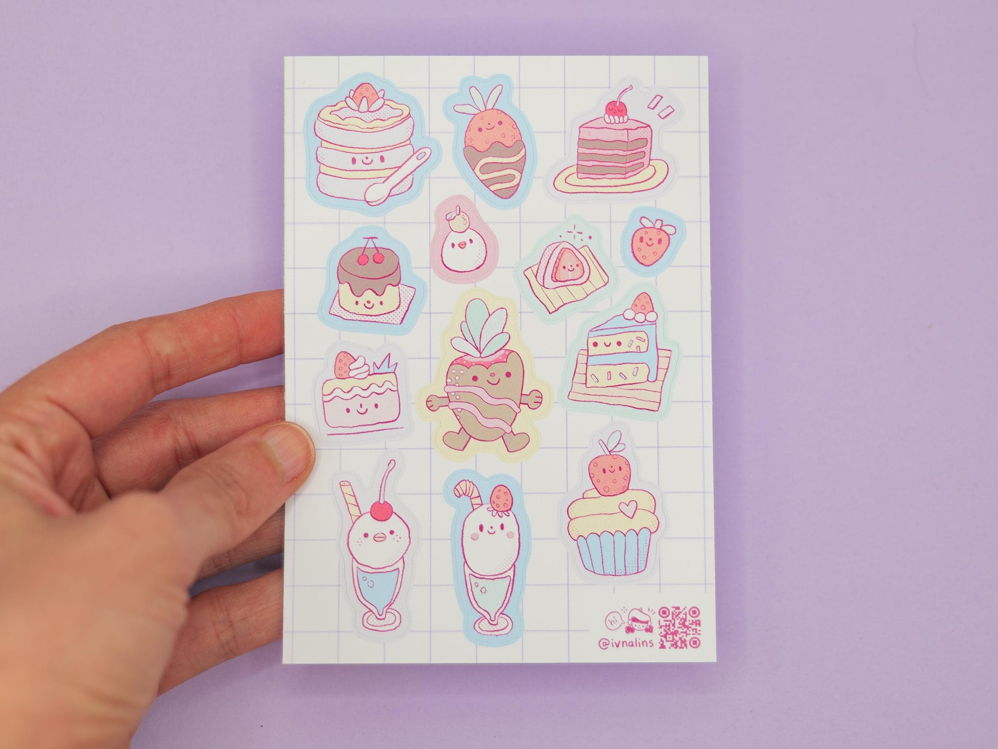 Sheet of cute illustrated stickers featuring cakes and desserts held by a hand on a purple background
