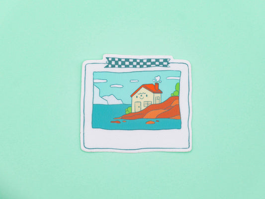 Sticker of a house by the sea on a light green background