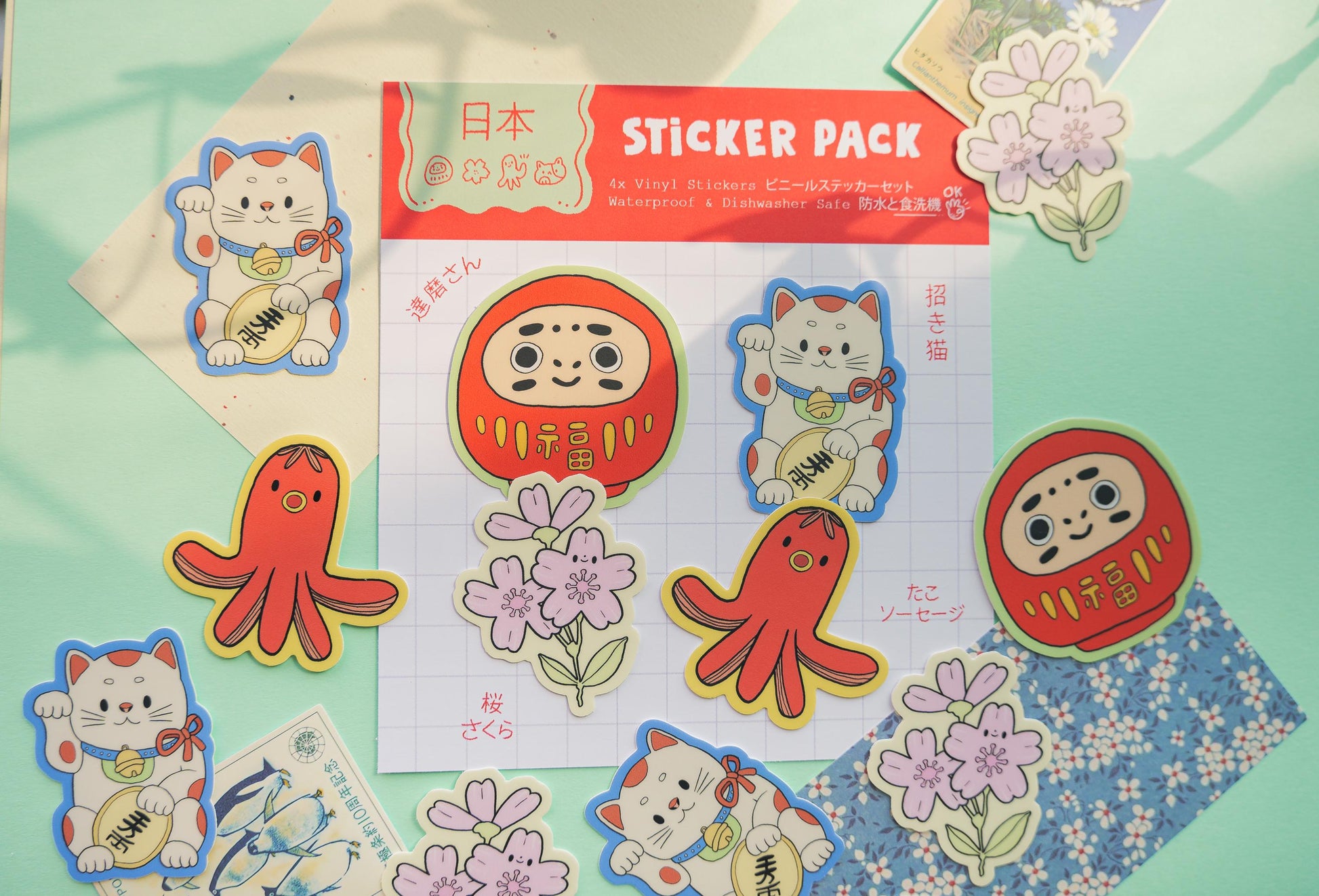 Sticker pack with cartoon characters on a colorful background. Daruma, Maneki-Neko, Sakura Flower and tako sausage
