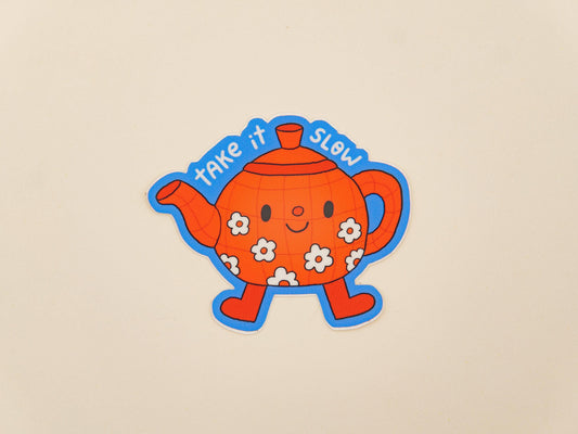 Cartoon teapot with flowers and 'take it SLOW' text on a beige background