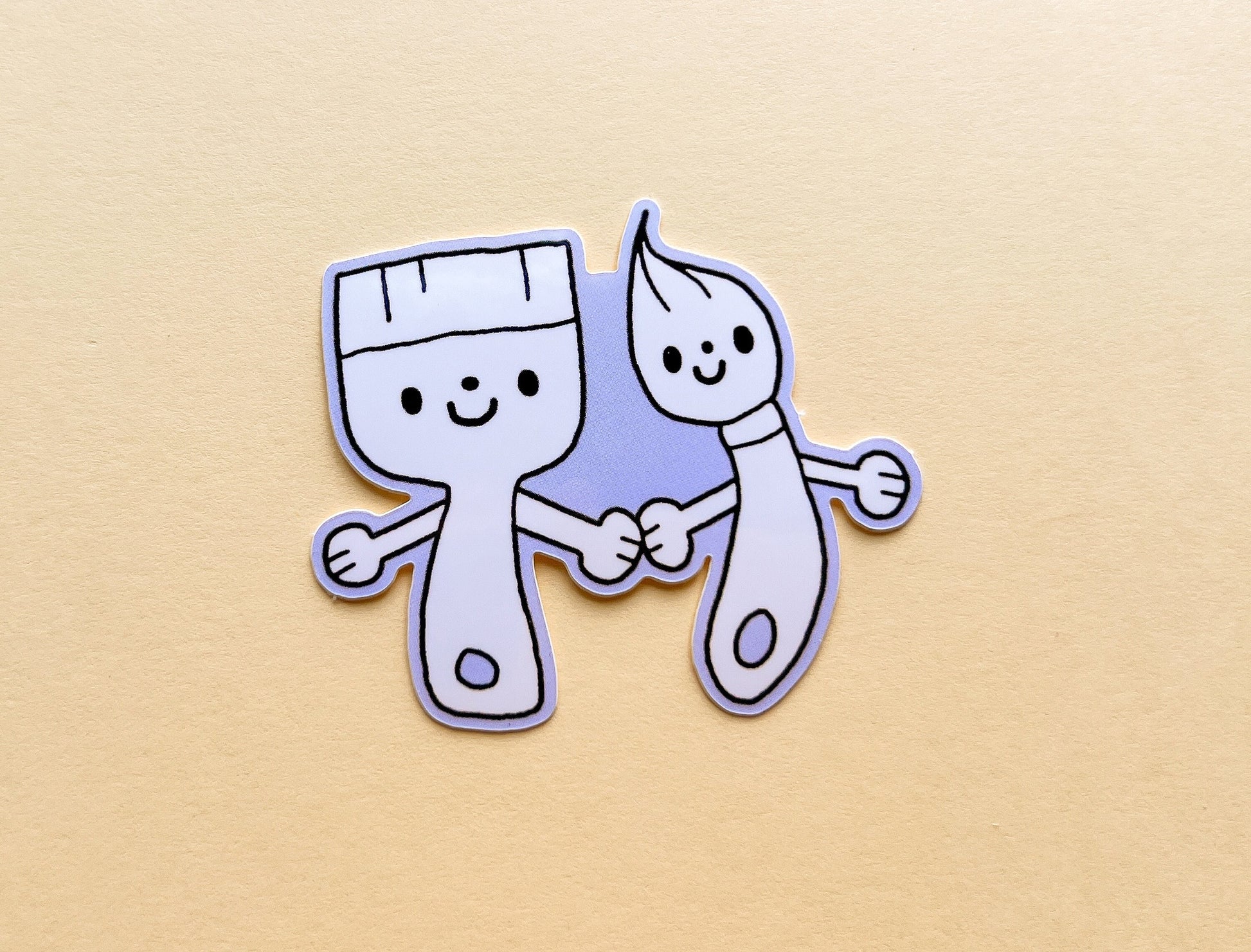 Cartoon-style paper cutout of a brush and a paint roller shaking hands on a beige background
