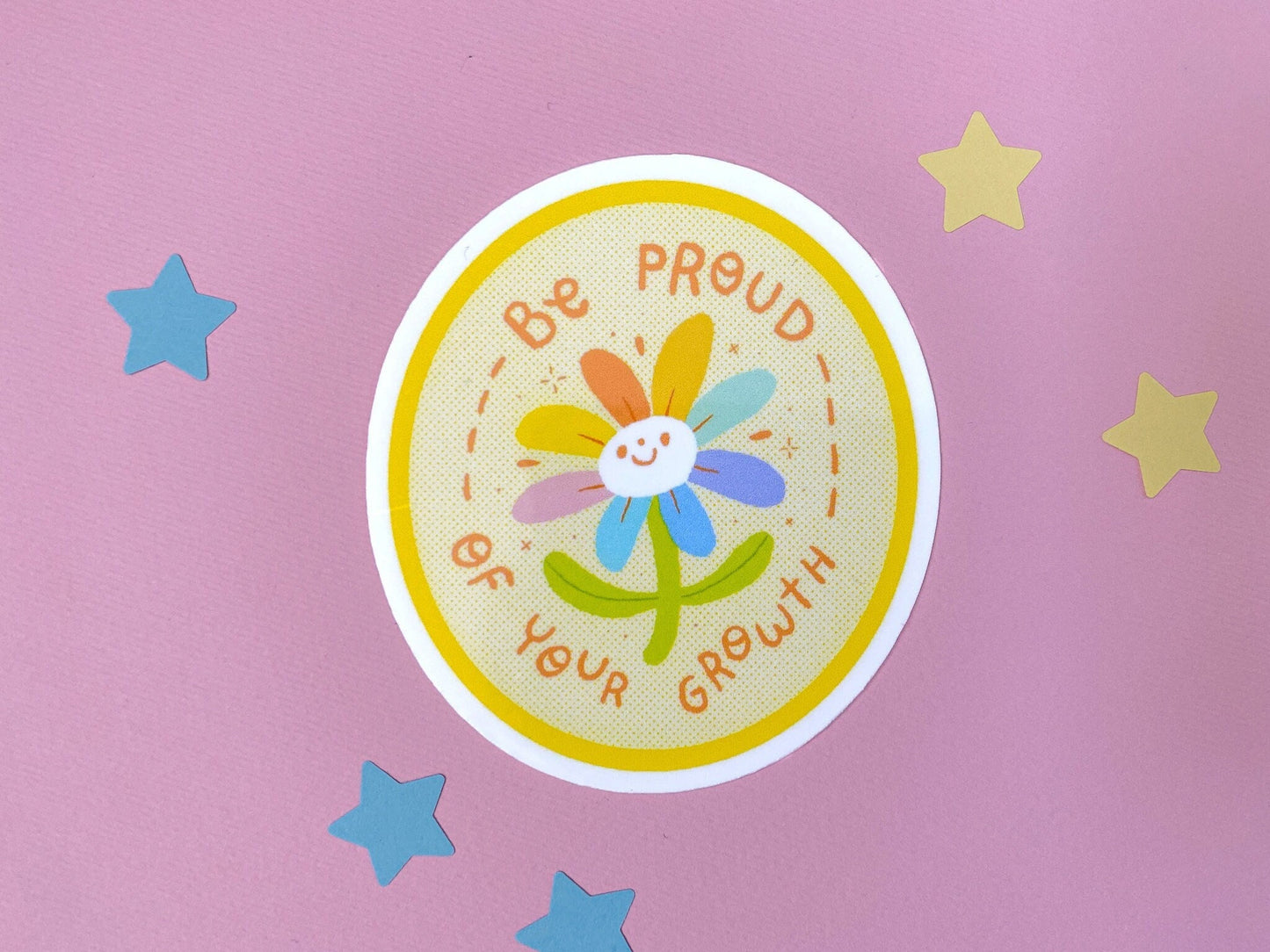Sticker with a flower and text 'Be proud of your growth' on a pink background with stars.