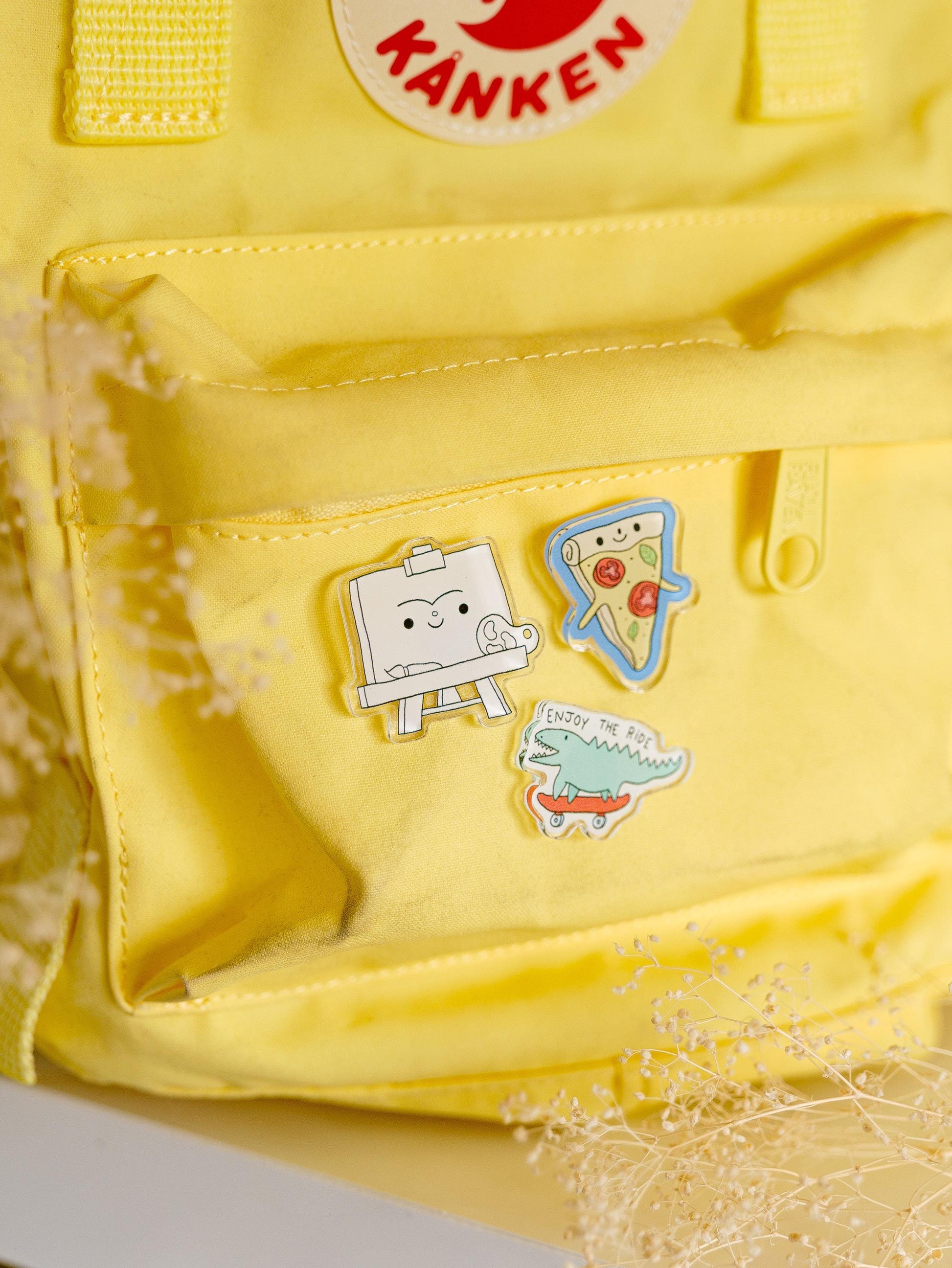 Yellow backpack with cartoon pins on a light background
