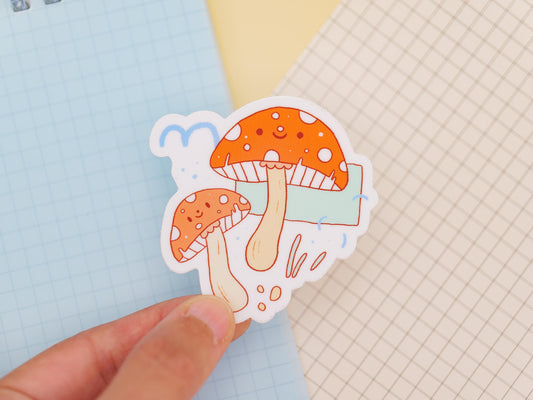 Sticker of mushrooms held by a hand on a light blue and grid-patterned background
