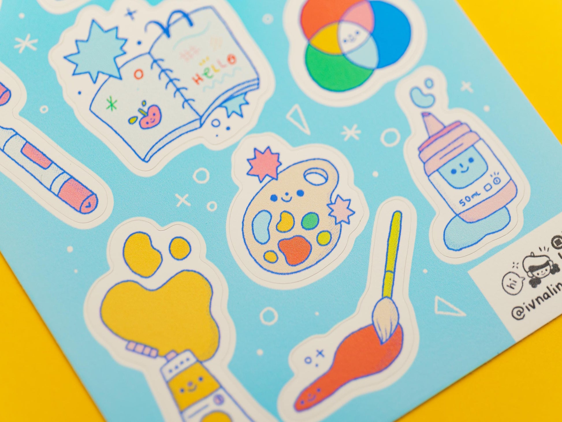 Stickers of art materials on a blue background with a yellow border