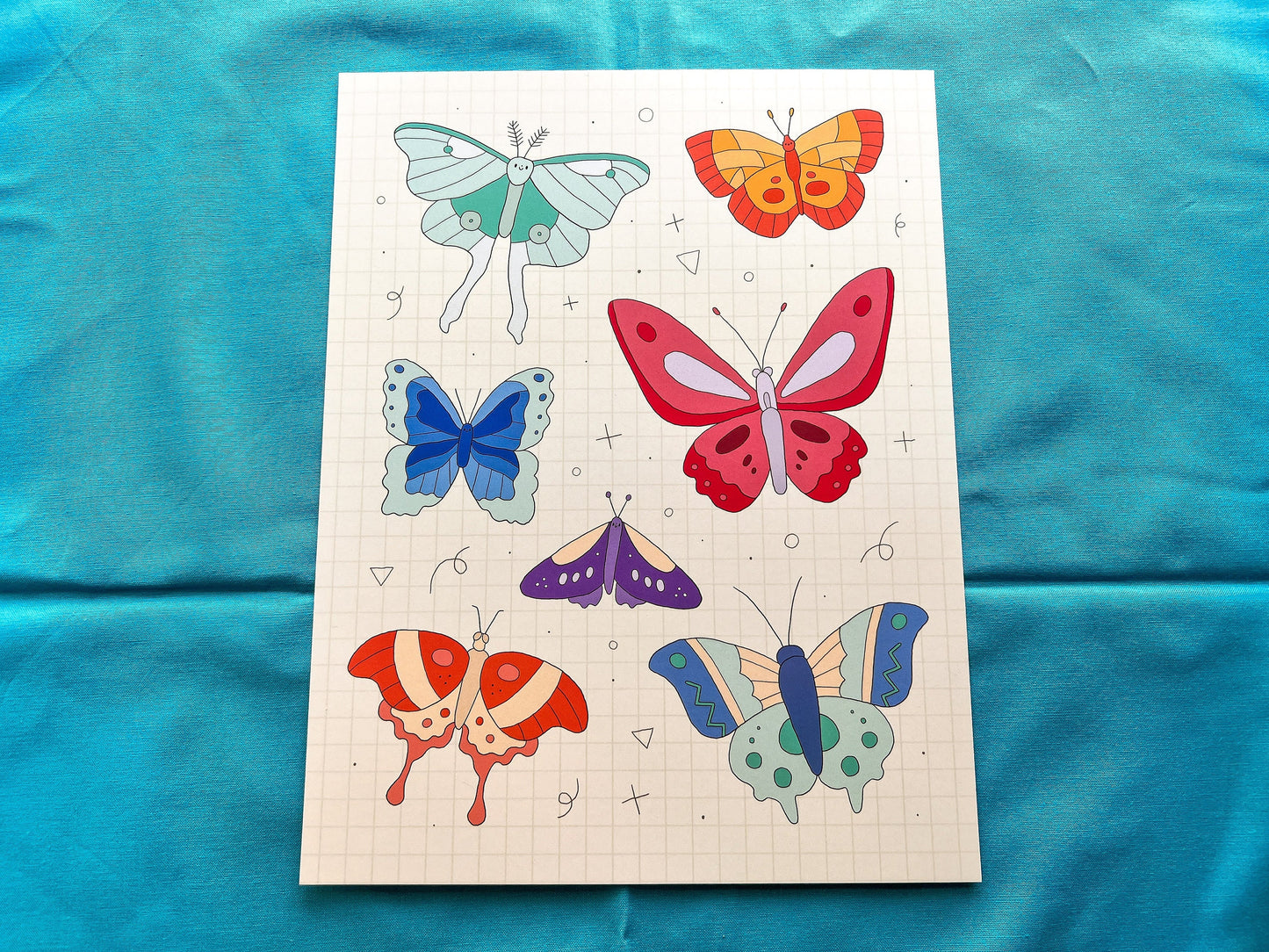 Sheet of butterfly drawings on a blue fabric background