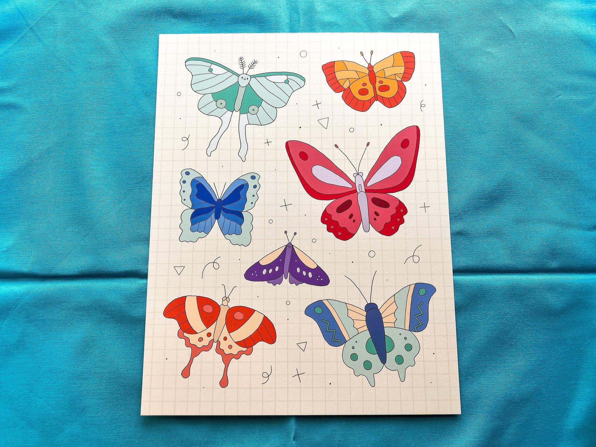 Sheet of butterfly drawings on a blue fabric background