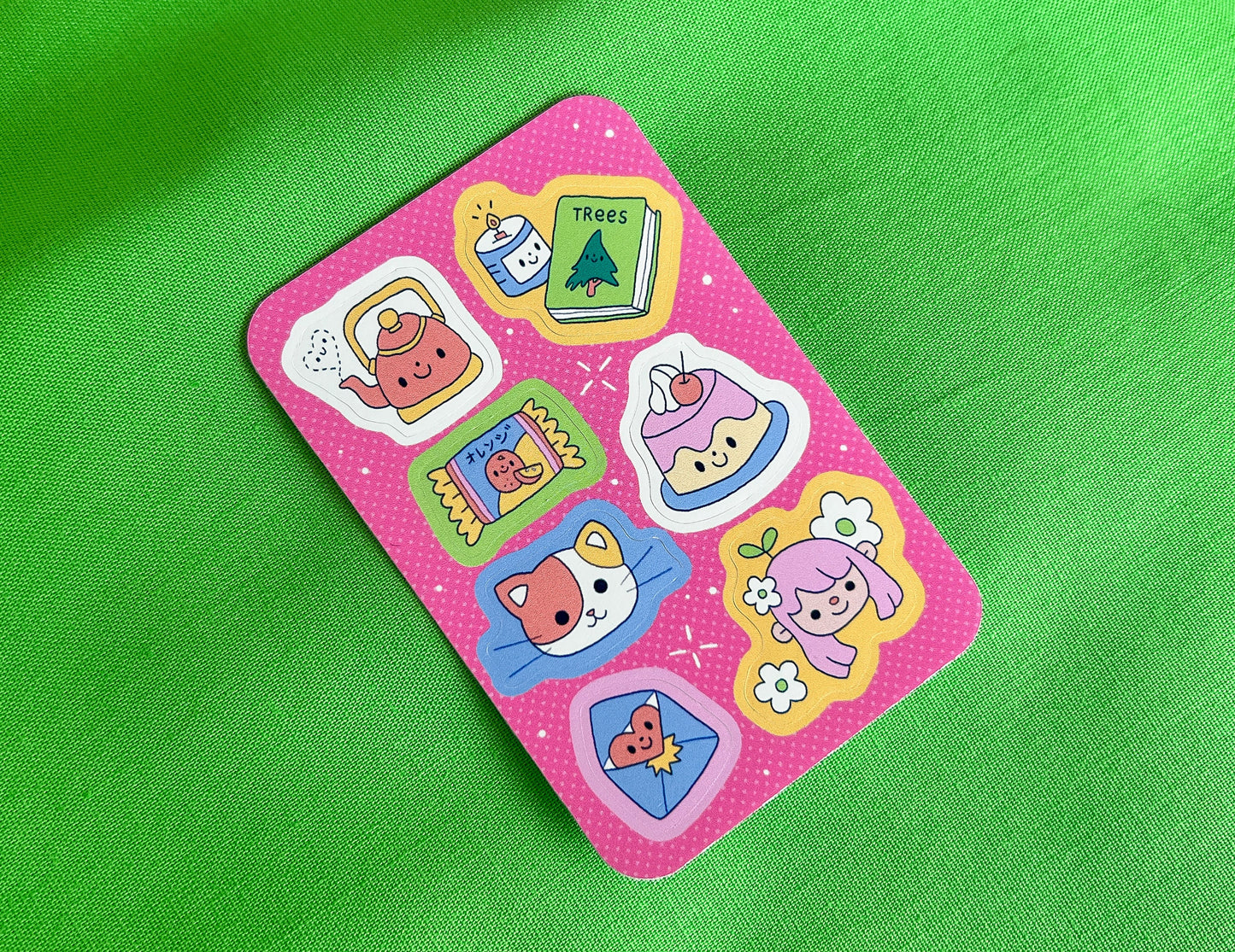 Set of colorful stickers on a pink card against a green background