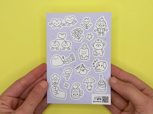 Sheet of cute illustrated stickers held by hands against a yellow background
